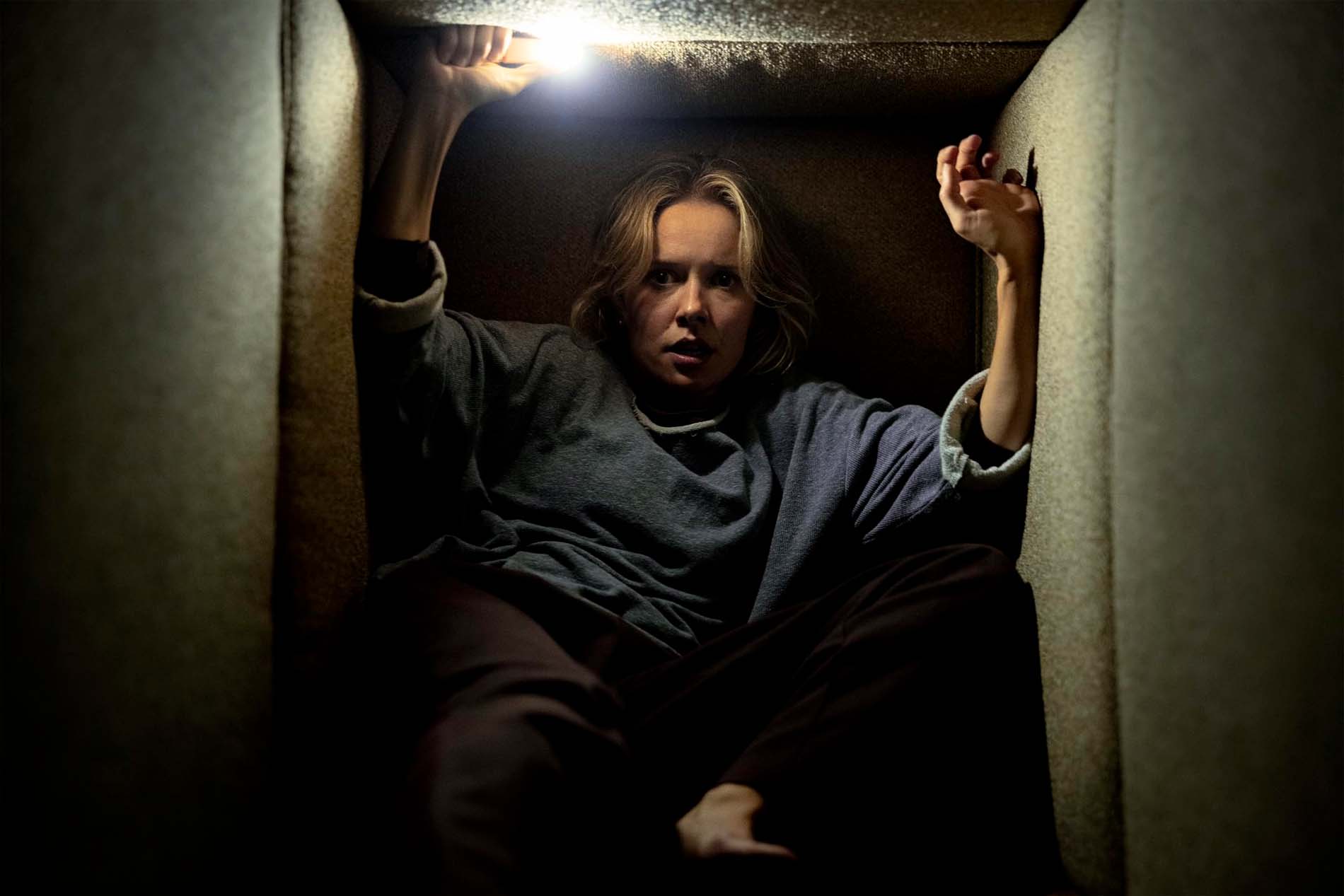 Gemma, interpretata da Amelia Eve, nascosta con una torcia in una scena di tensione di Insidious: Fuori dall'Altrove
