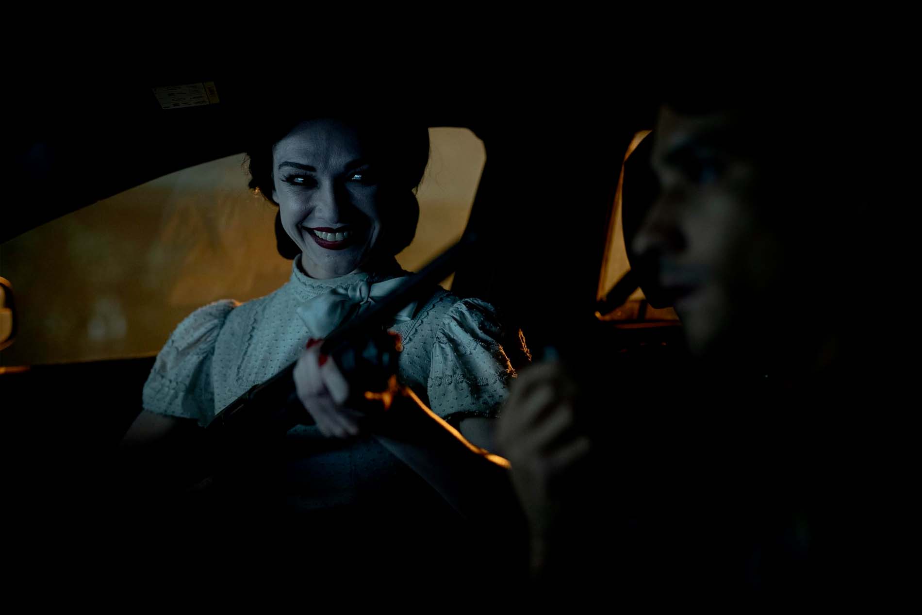 Entità sinistra sorridente all'interno di un'auto in una scena horror notturna di Insidious: Fuori dall'Altrove