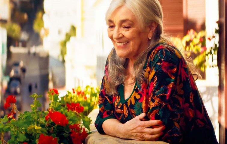 Locandina di Calle Málaga: Carmen Maura sorridente affacciata al balcone tra i gerani rossi, sullo sfondo i vicoli di Tangeri