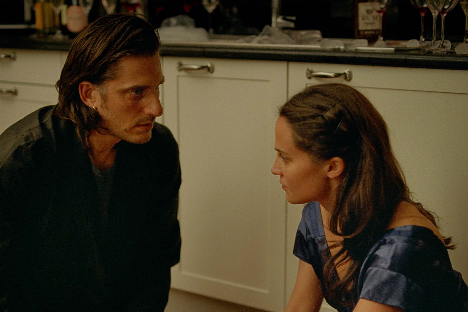 Luca Marinelli e Alicia Vikander in una scena di The Echo Chamber, faccia a faccia in una cucina